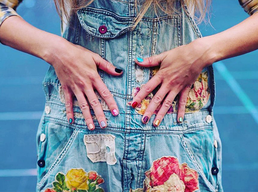 Woman wearing Magnolia Pearl denim overalls with vintage floral patches and whimsical artisan style