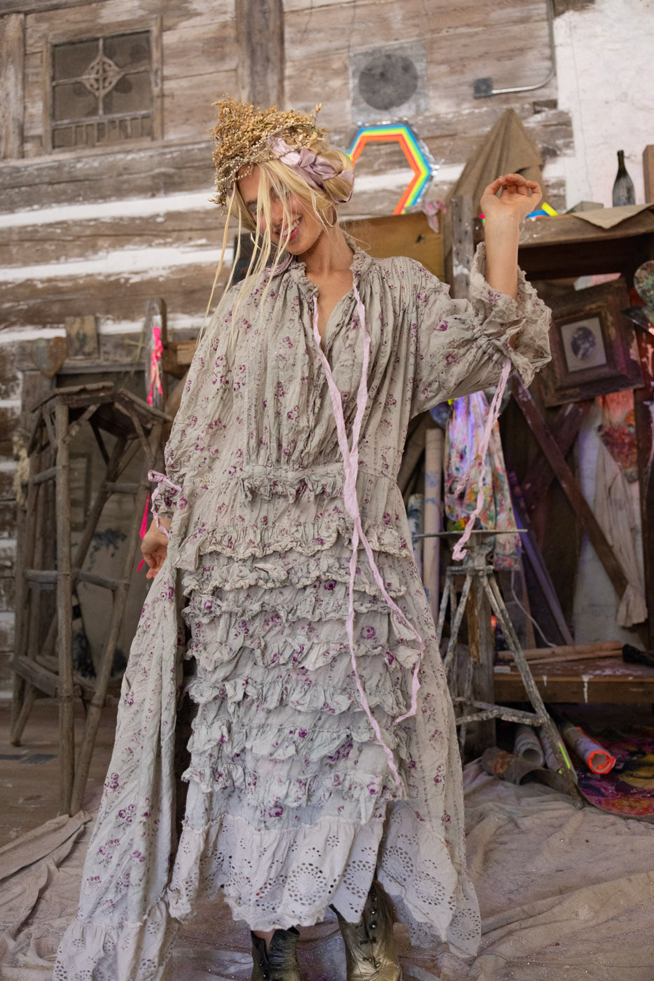 Person in a long, floral dress with a hat in a rustic indoor setting