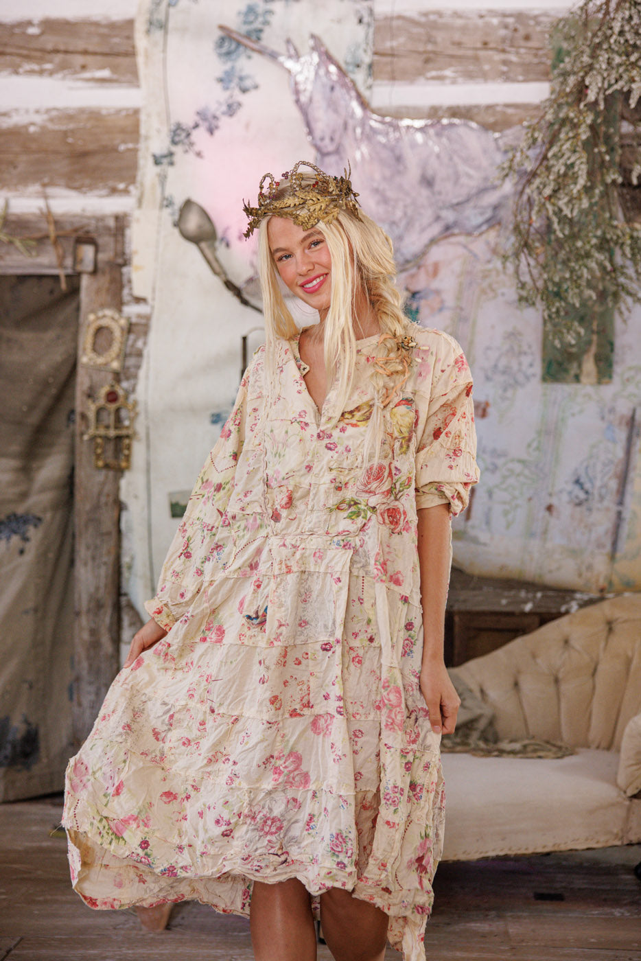Woman in Magnolia Pearl vintage floral dress and crown, whimsical artisan style, rustic setting