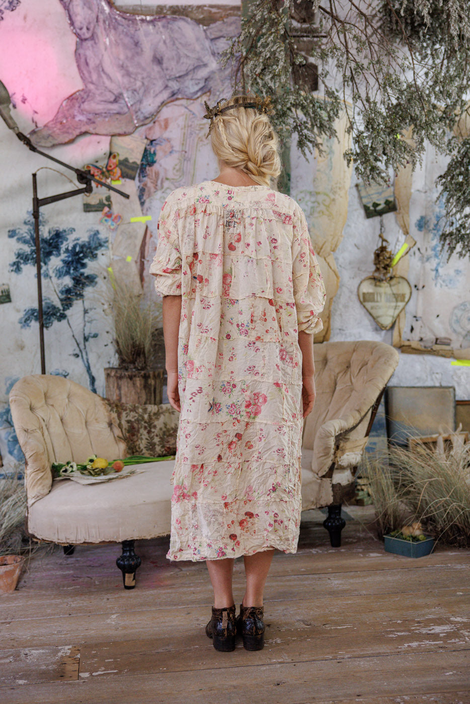Woman in Magnolia Pearl vintage floral dress, whimsical artisan style, standing in eclectic room