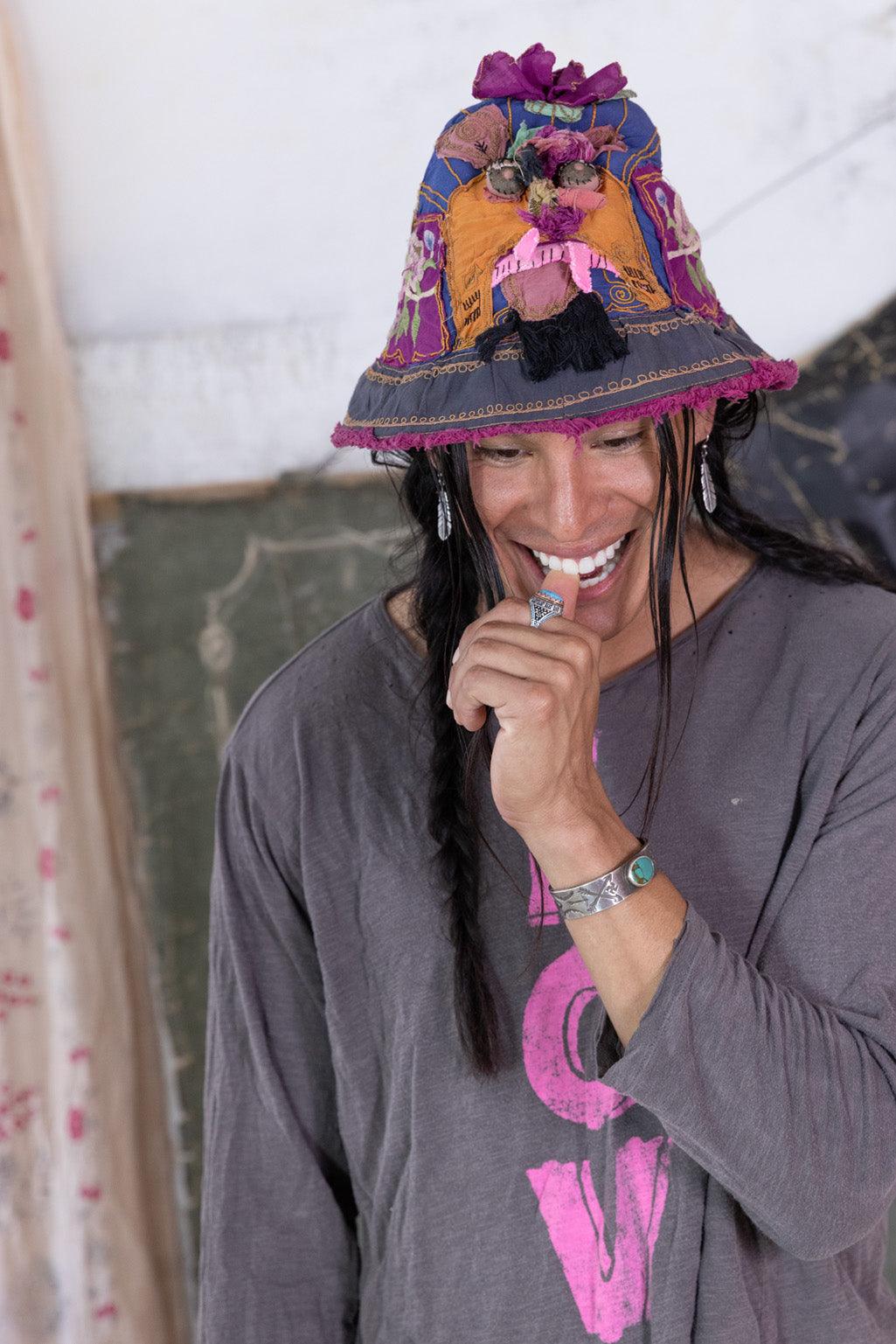 Magnolia Pearl artisan patchwork bucket hat with vintage whimsical floral details, worn by smiling model in gray LOVE shirt