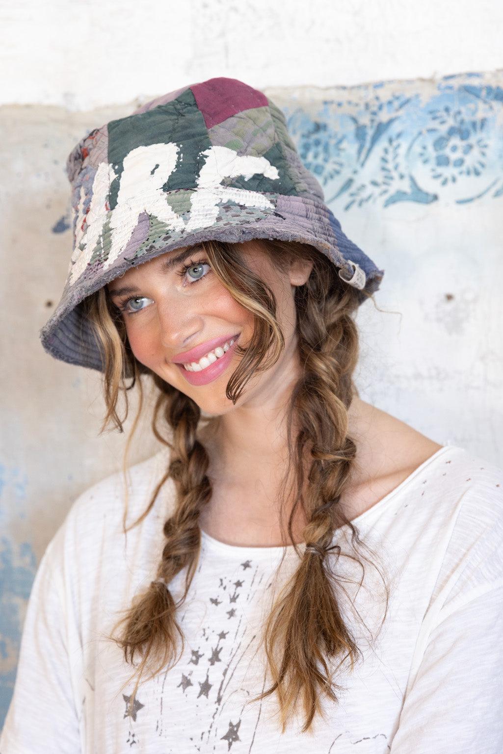 Woman in Magnolia Pearl artisan patchwork bucket hat and vintage-style graphic tee with braids