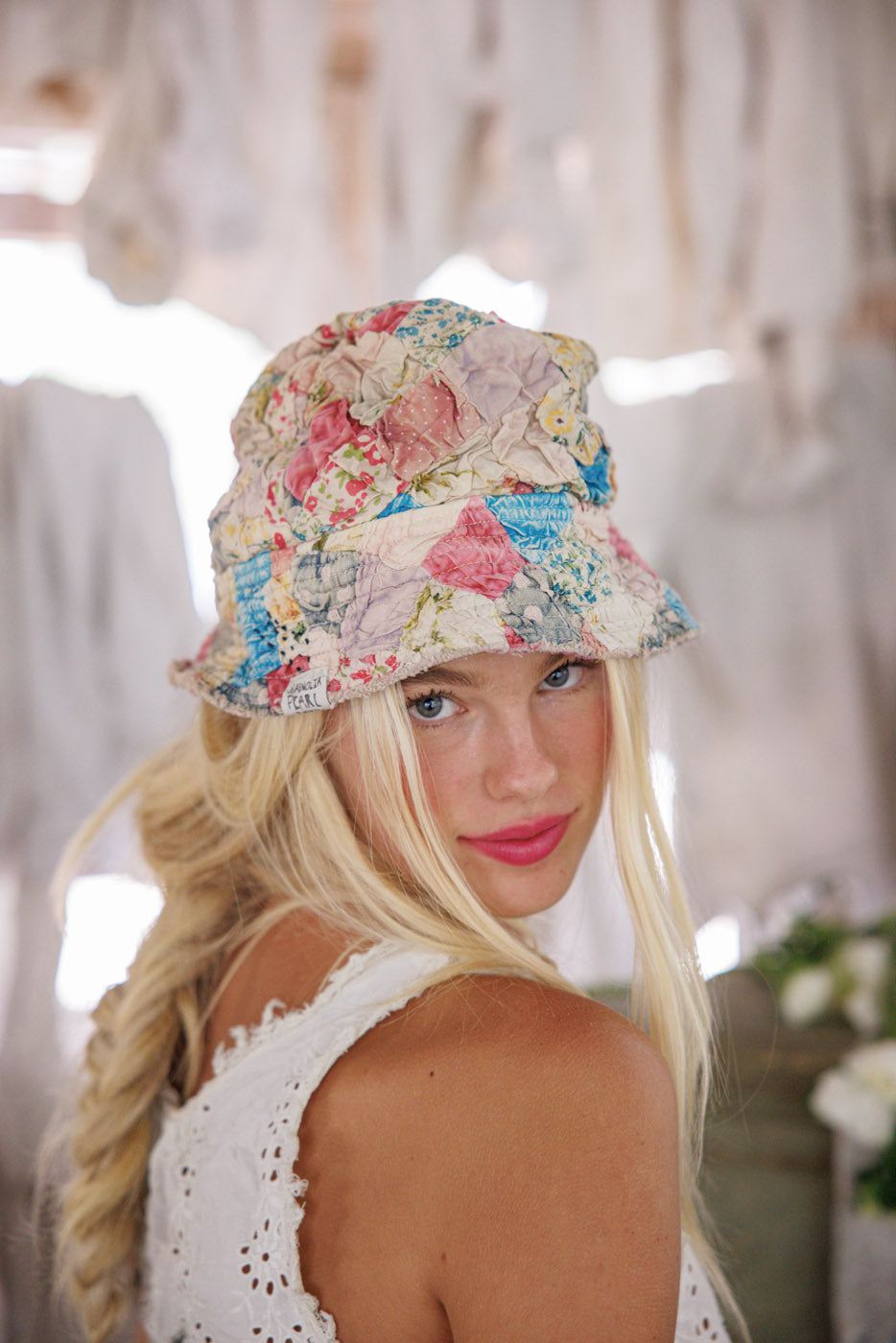 Blonde woman in Magnolia Pearl quilted patchwork bucket hat, vintage lace top, artisan boho style
