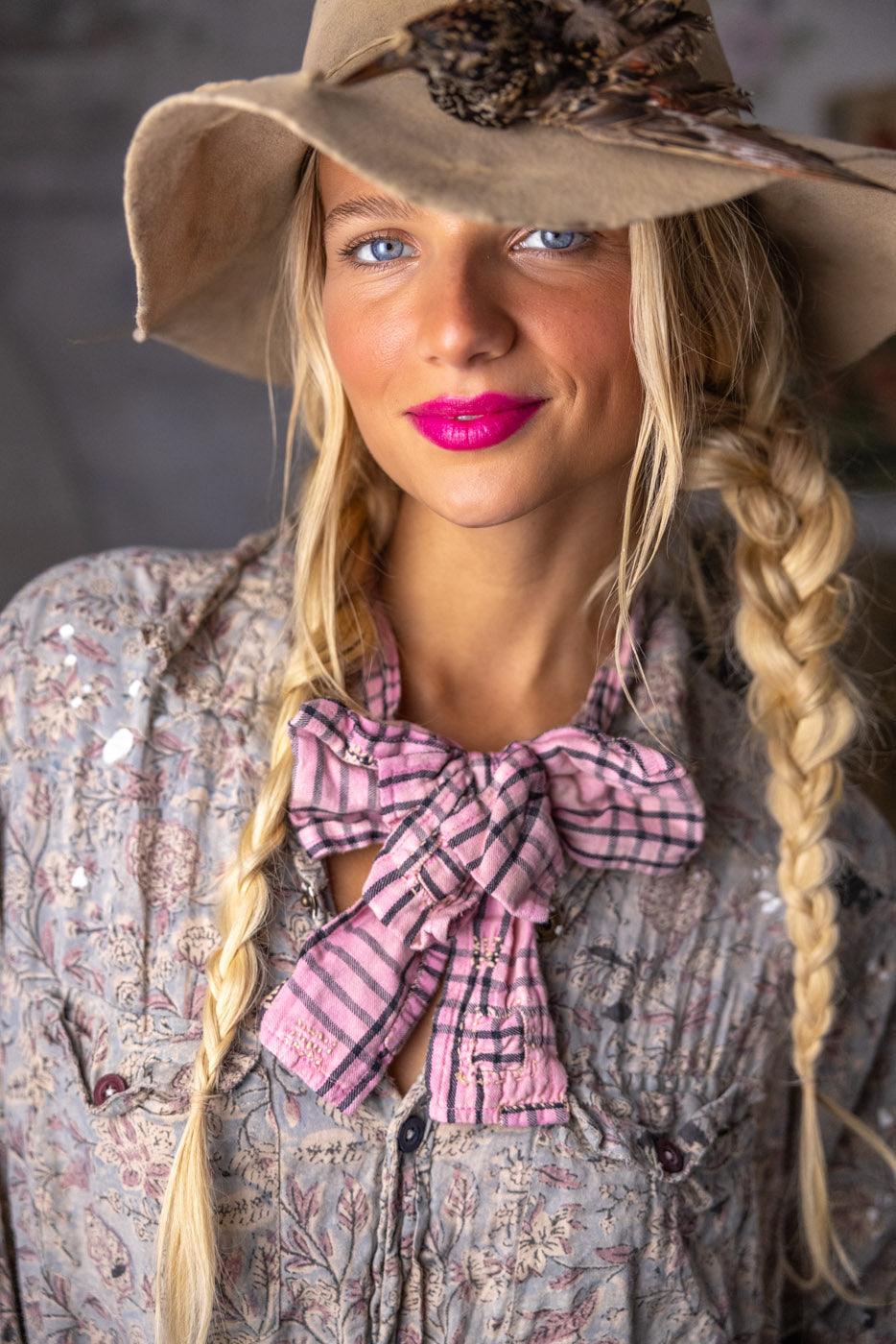 Woman in Magnolia Pearl artisan vintage floral shirt, patchwork skirt, and whimsical feather hat
