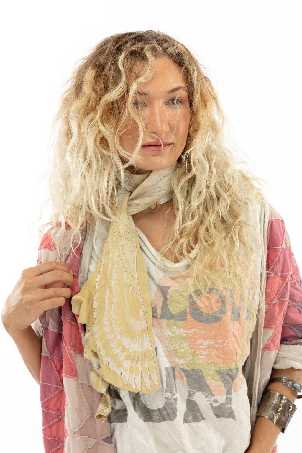 Woman models Magnolia Pearl artisan jacket with whimsical patchwork design, vintage distressed pants and boho shoes on white background.