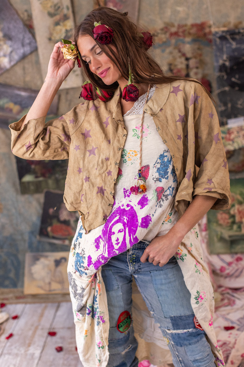 Woman in Magnolia Pearl artisan clothing with whimsical vintage style, hanging art on floral wall