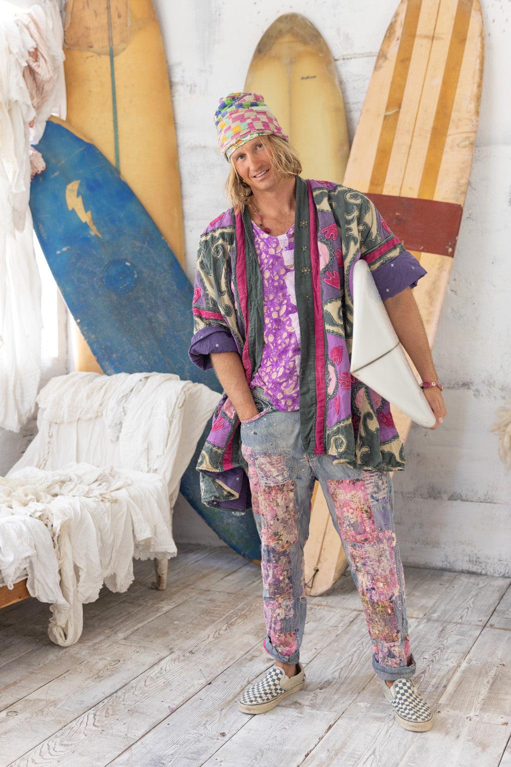 Man in Magnolia Pearl artisan jacket, whimsical patchwork pants, vintage surfer style, surfboards