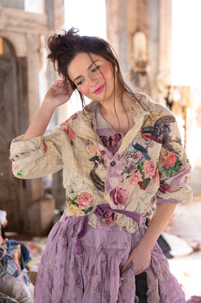 Woman in Magnolia Pearl artisan jacket with bird and floral prints, vintage lavender dress