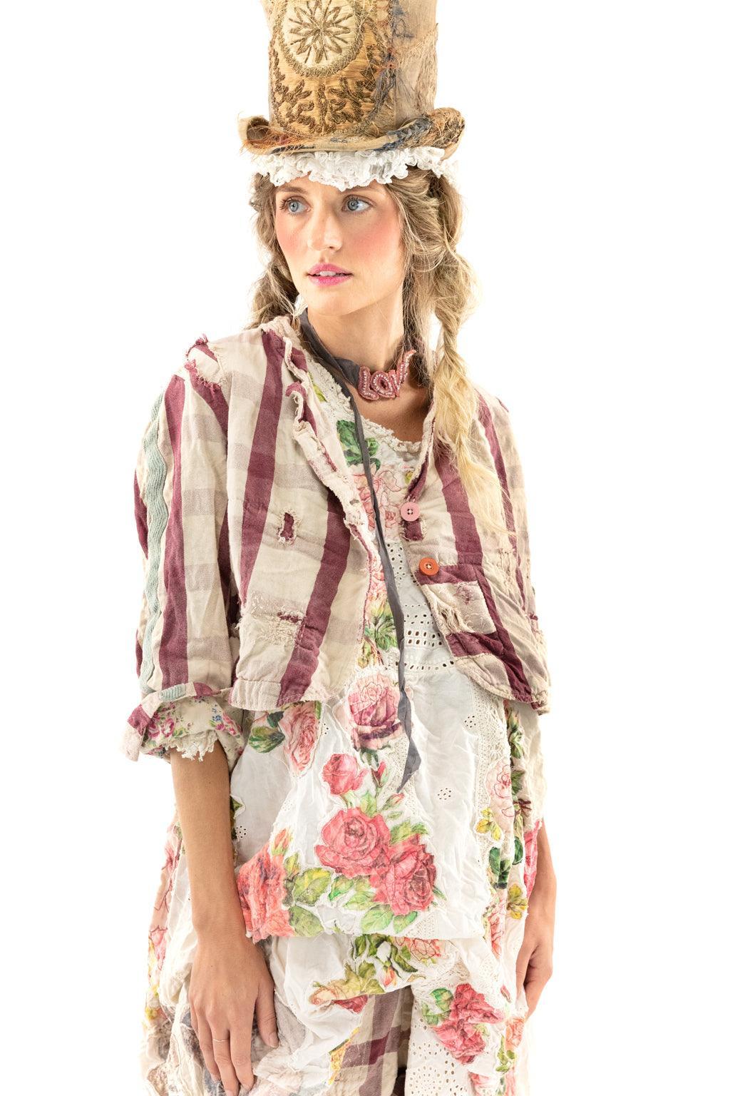 Woman in Magnolia Pearl whimsical floral quilted jacket, vintage-style artisan top hat, checkered pants, and lace boots