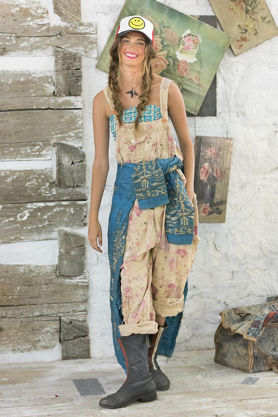 Woman in Magnolia Pearl vintage floral overalls, artisan whimsical design, standing indoors