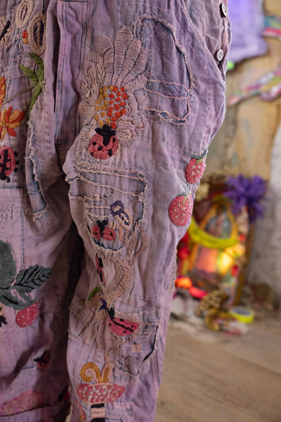 Embroidered pants with colorful designs and lady bug embroidered patches.