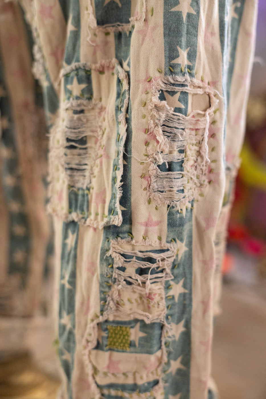 Close-up of a textured fabric pants with star patterns and frayed edges.