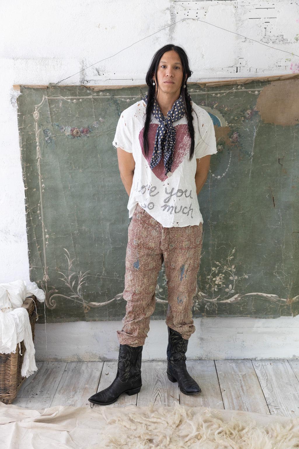 Model in Magnolia Pearl artisan vintage pants, whimsical t-shirt, and cowboy boots, rustic setting