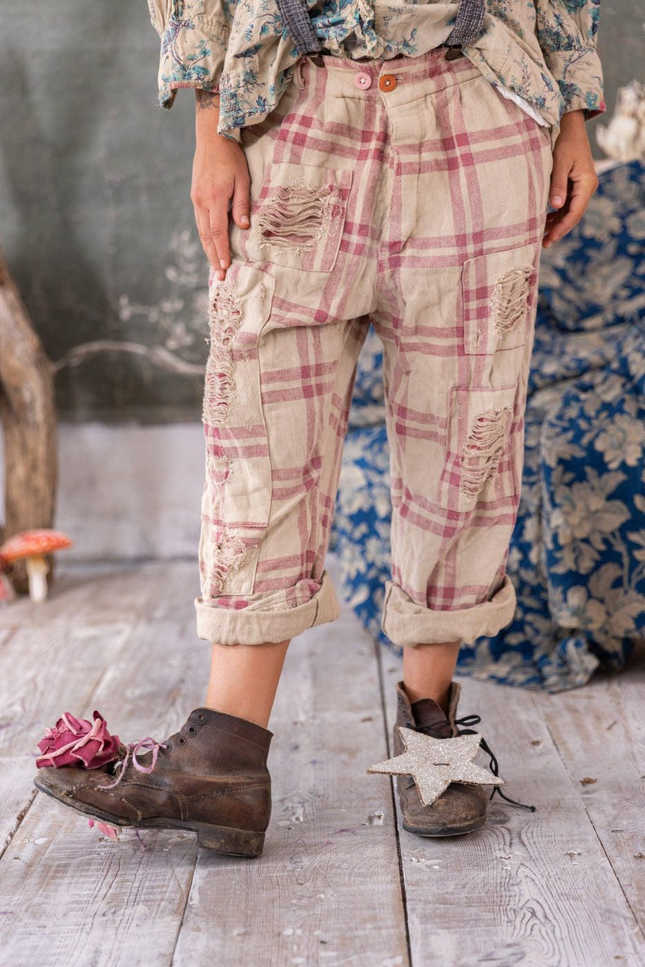 Magnolia Pearl artisan pants with whimsical patchwork, vintage plaid, worn by model in rustic setting