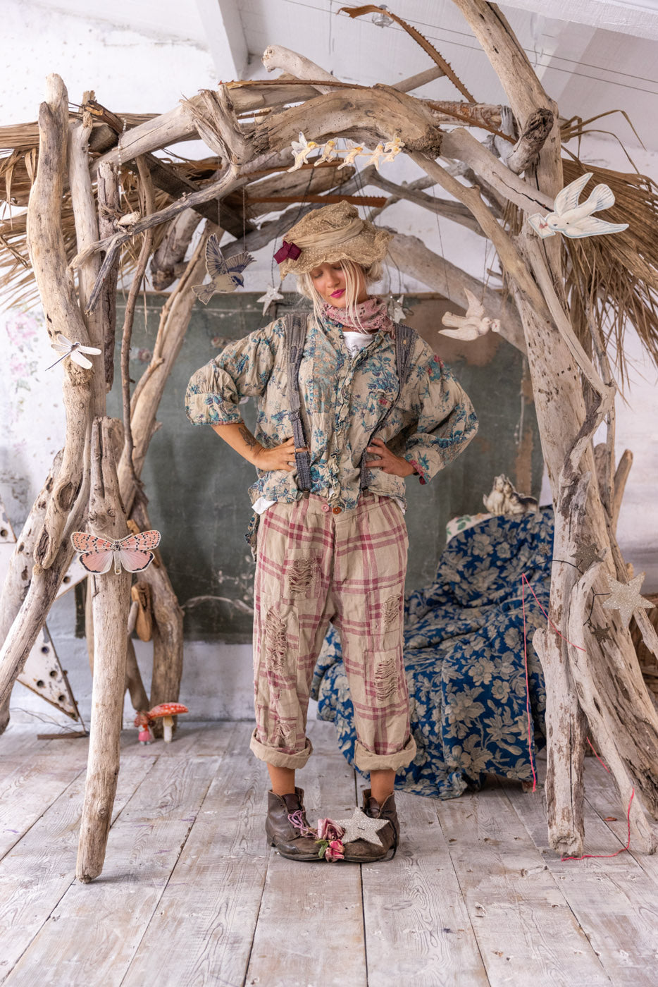 Magnolia Pearl artisan pants with whimsical patchwork, vintage plaid, worn by model in rustic setting