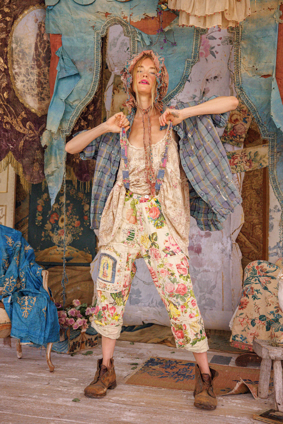 Woman in Magnolia Pearl artisan vintage floral pants and whimsical bonnet, sitting in boho setting
