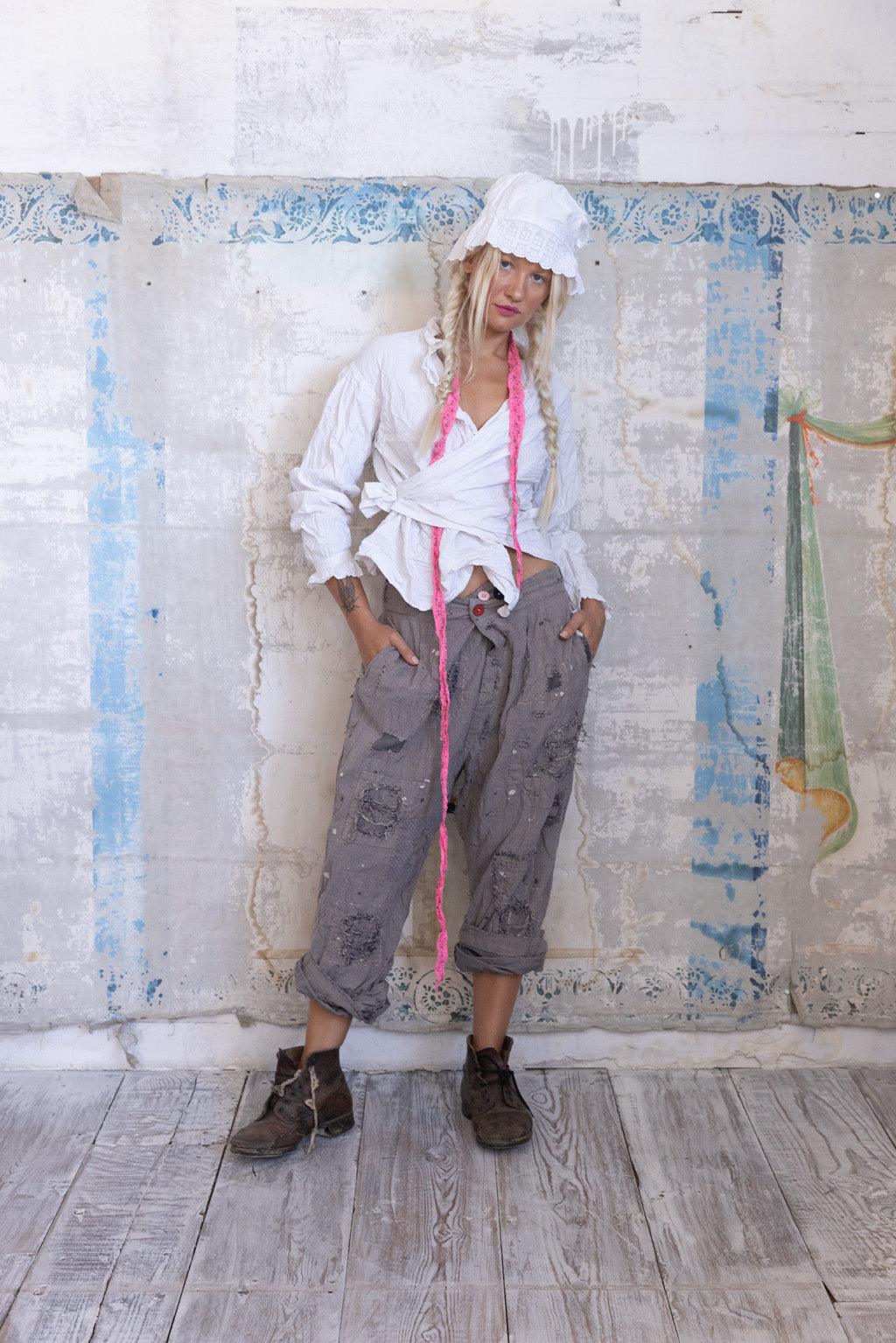 Woman in Magnolia Pearl artisan vintage patchwork pants, white blouse, bonnet, rustic setting