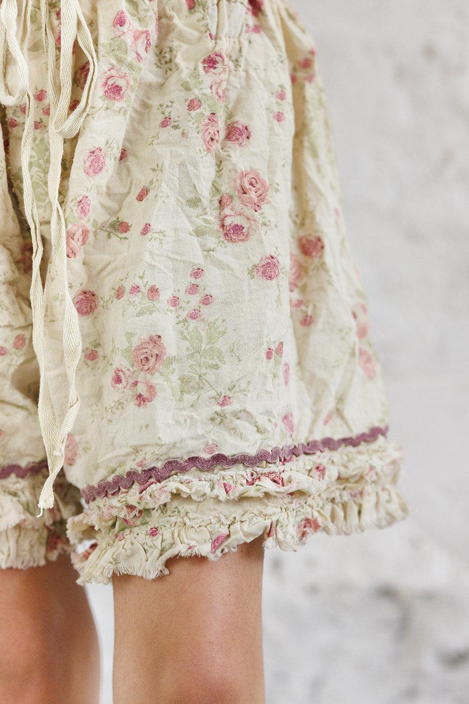 Magnolia Pearl artisan floral shorts with ruffle trim and whimsical vintage style, modeled indoors
