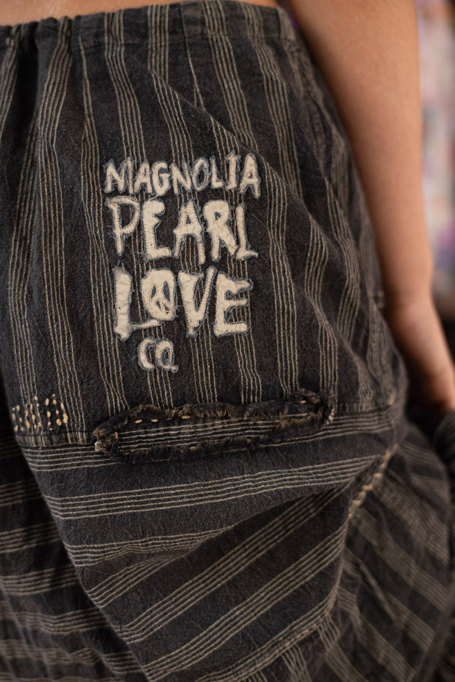 Close-up of a striped skirt with 'Magnolia Pearl Love Co.' text on a blurred background