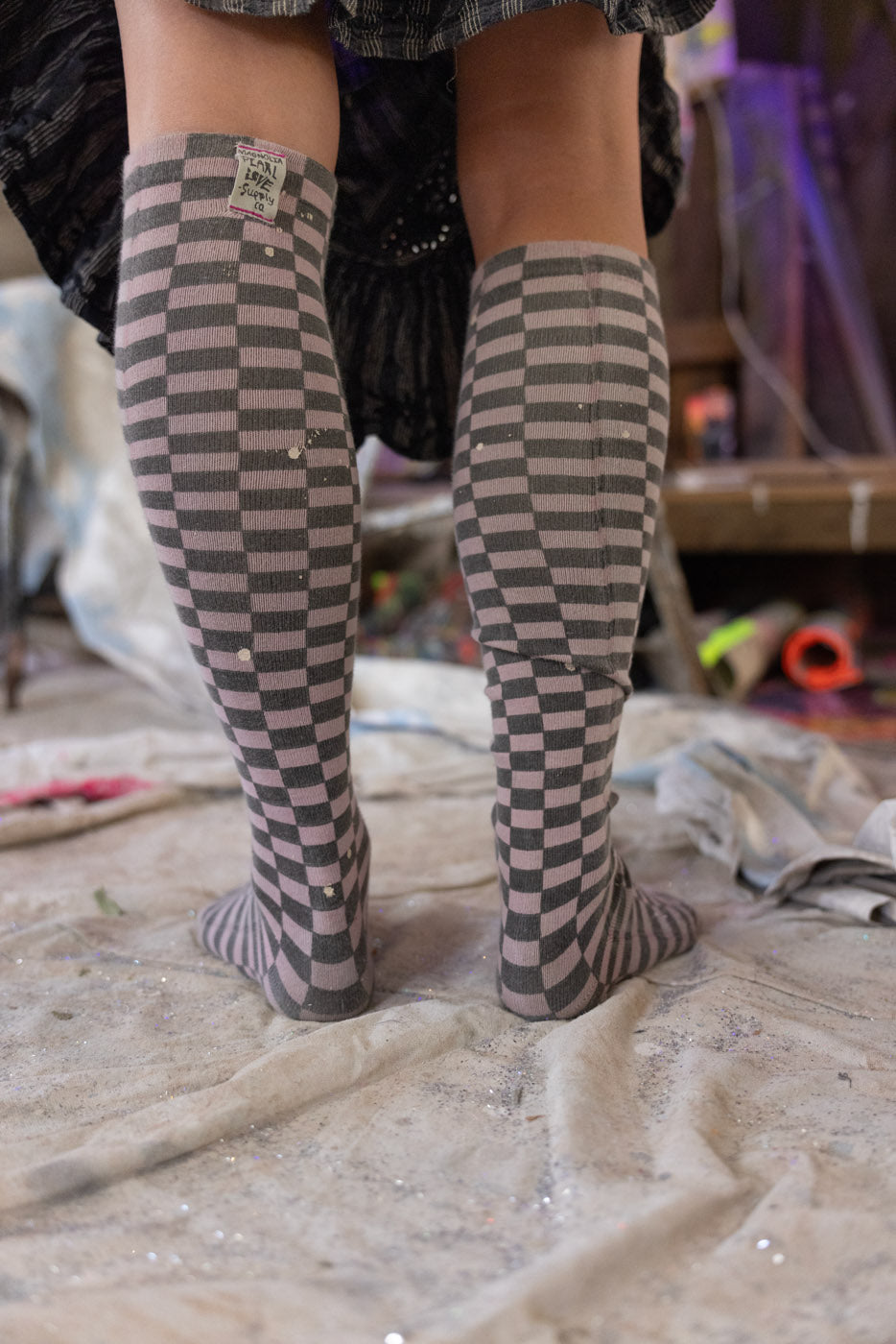 Person wearing checkered knee-high socks in an artistic setting with a blurred background