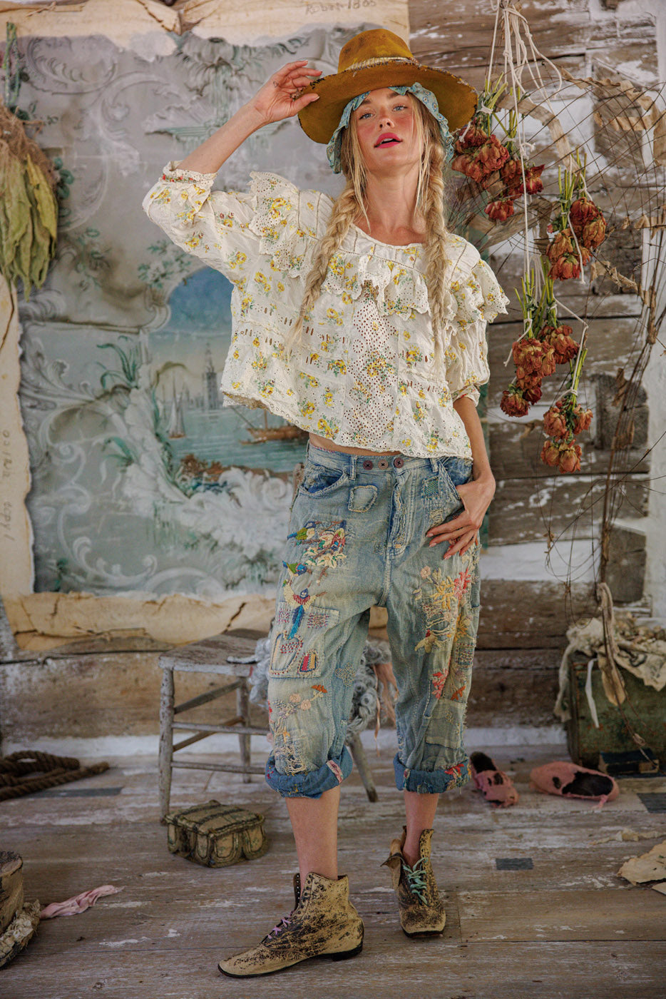 Woman in Magnolia Pearl vintage floral lace blouse and embroidered jeans, rustic setting, artisan whimsical style