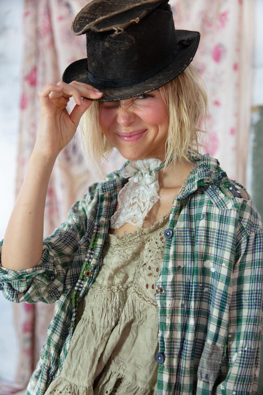 Woman in Magnolia Pearl artisan vintage lace dress, plaid shirt, and whimsical top hat