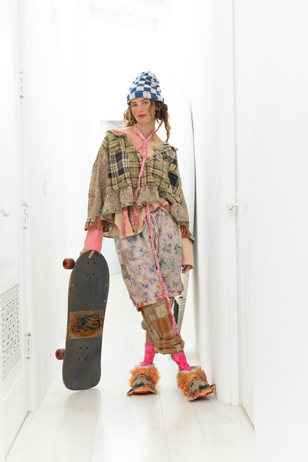 Model in Magnolia Pearl artisan vintage patchwork clothing, whimsical style, skateboard, hallway
