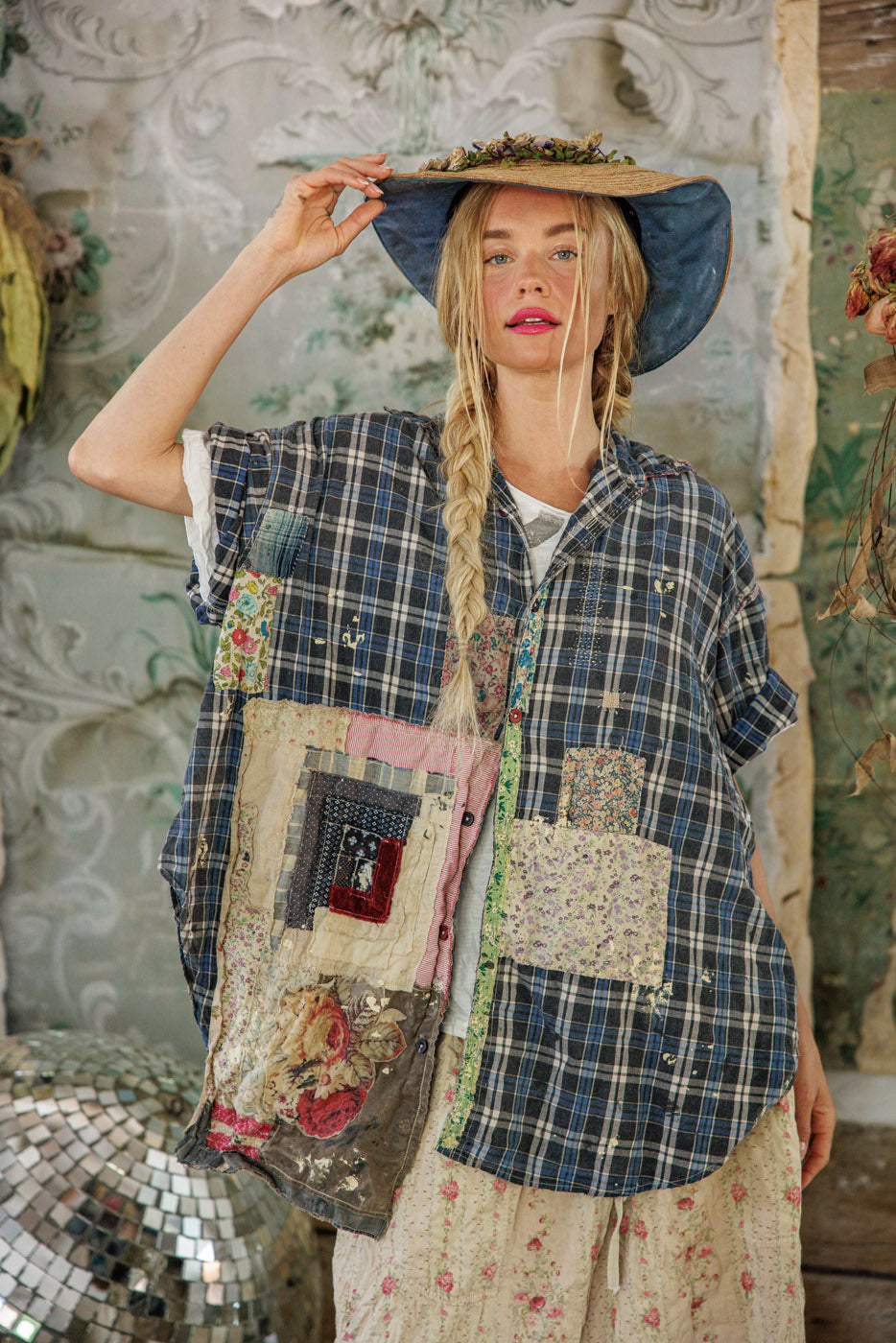 Woman in Magnolia Pearl artisan plaid patchwork shirt and floral hat, vintage whimsical style