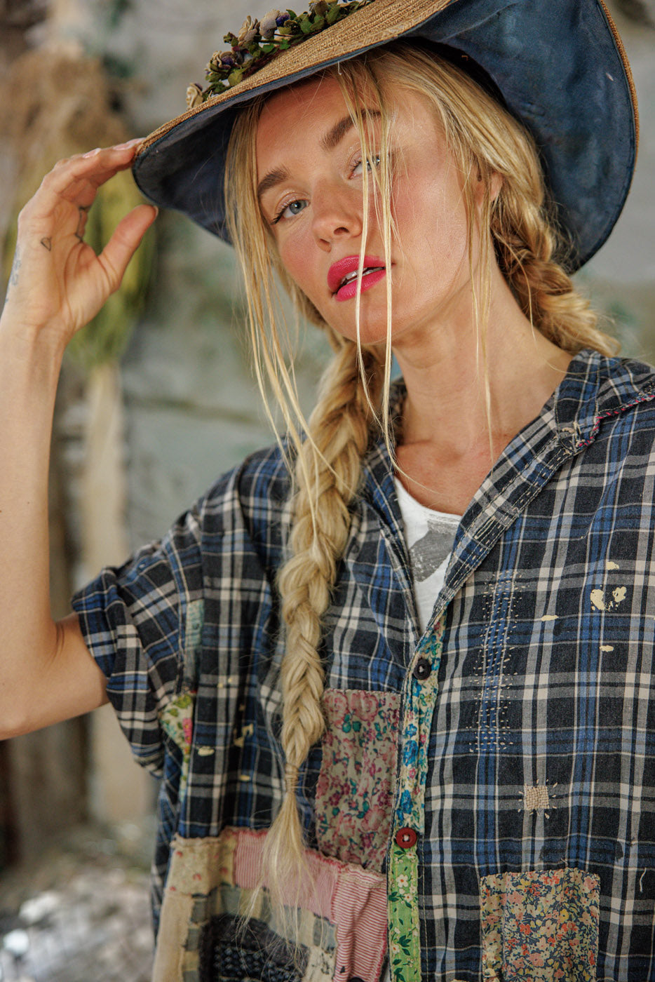 Woman in Magnolia Pearl artisan plaid shirt with whimsical patchwork, vintage straw hat