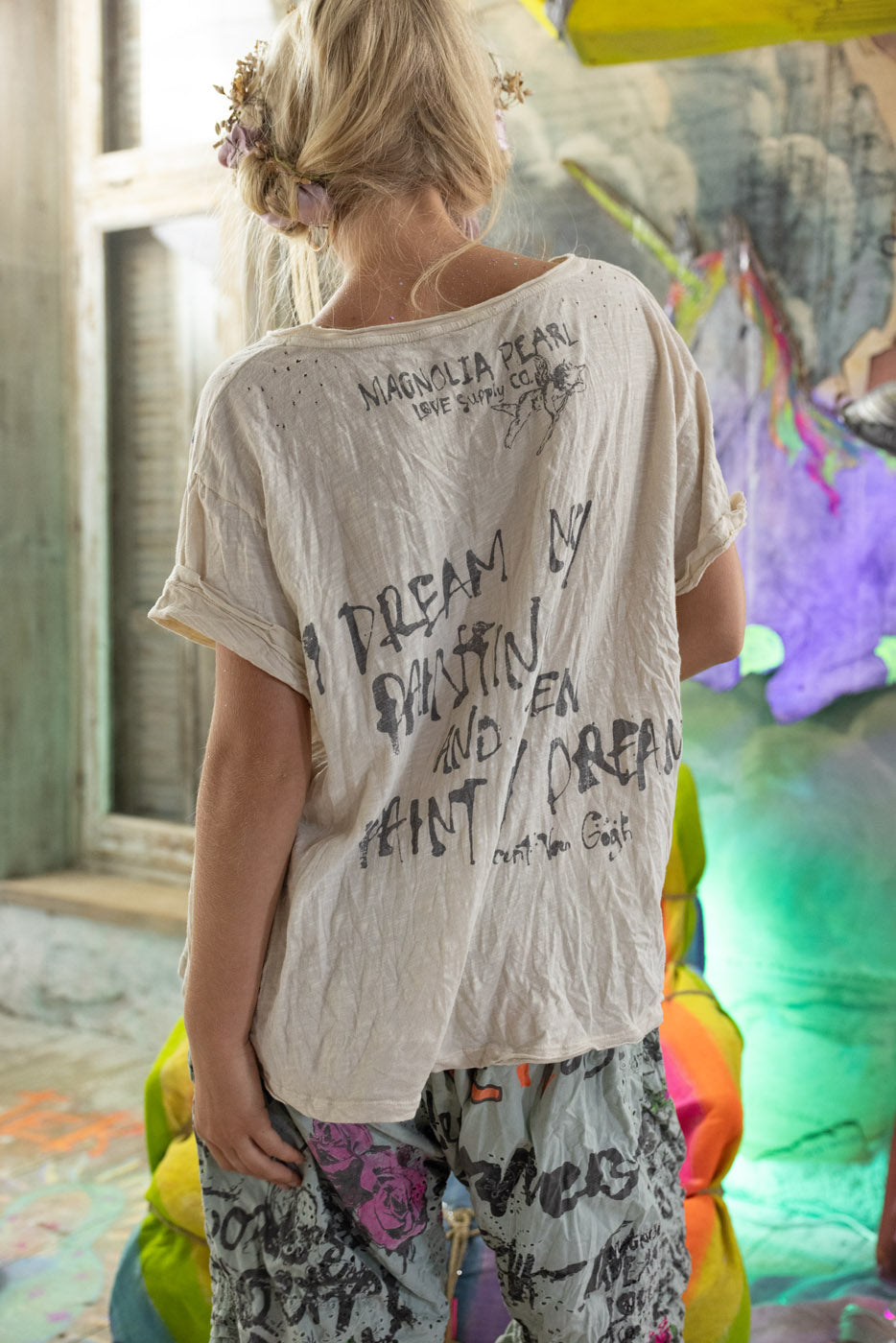 Person wearing a white t-shirt with text, standing in a colorful indoor setting. Vincent van gogh quote on t-shirt.
"I dream my painting and then I paint my dream"