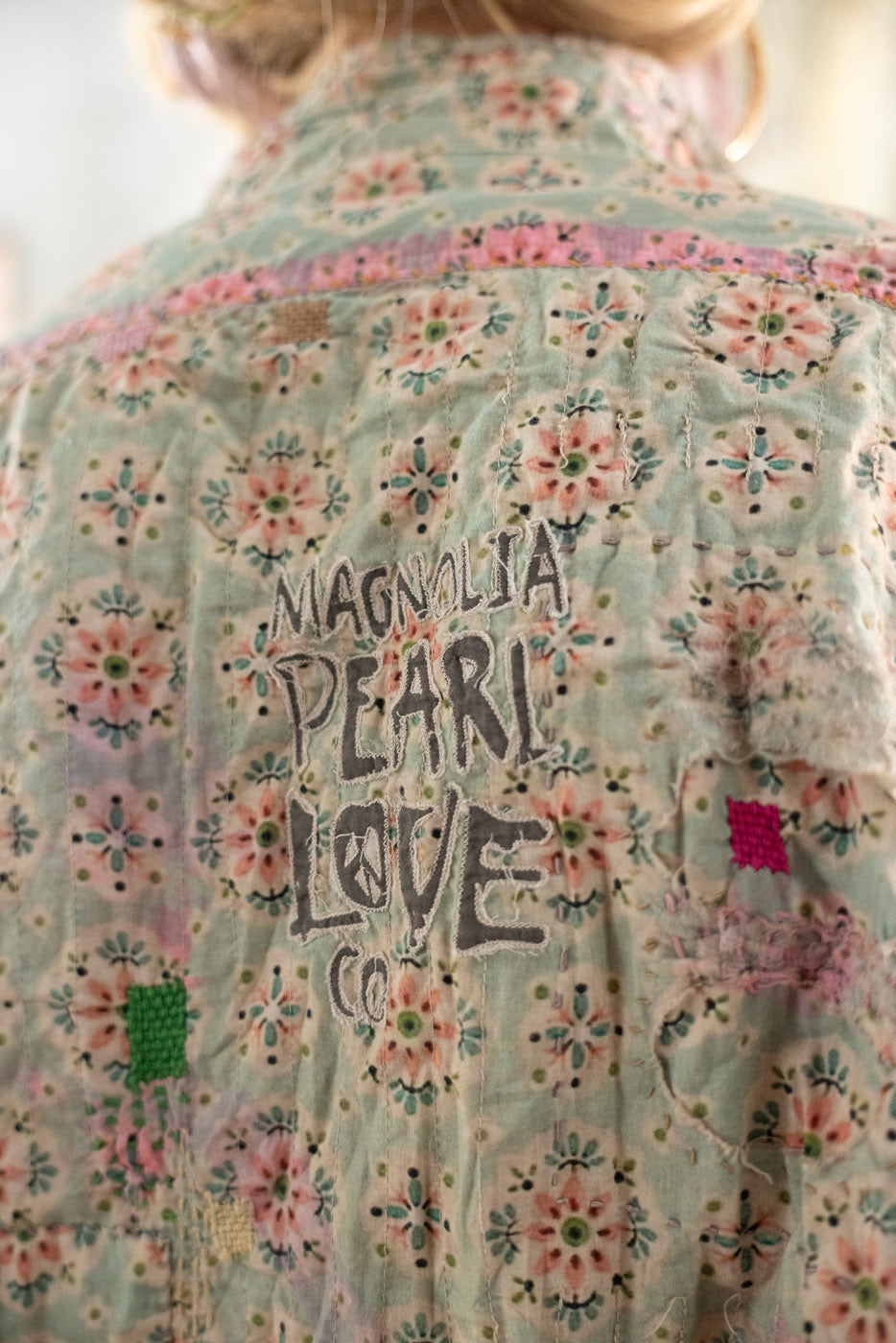 Floral patterned shirt with 'MAGNOLIA PEARL LOVE CO' text on the back