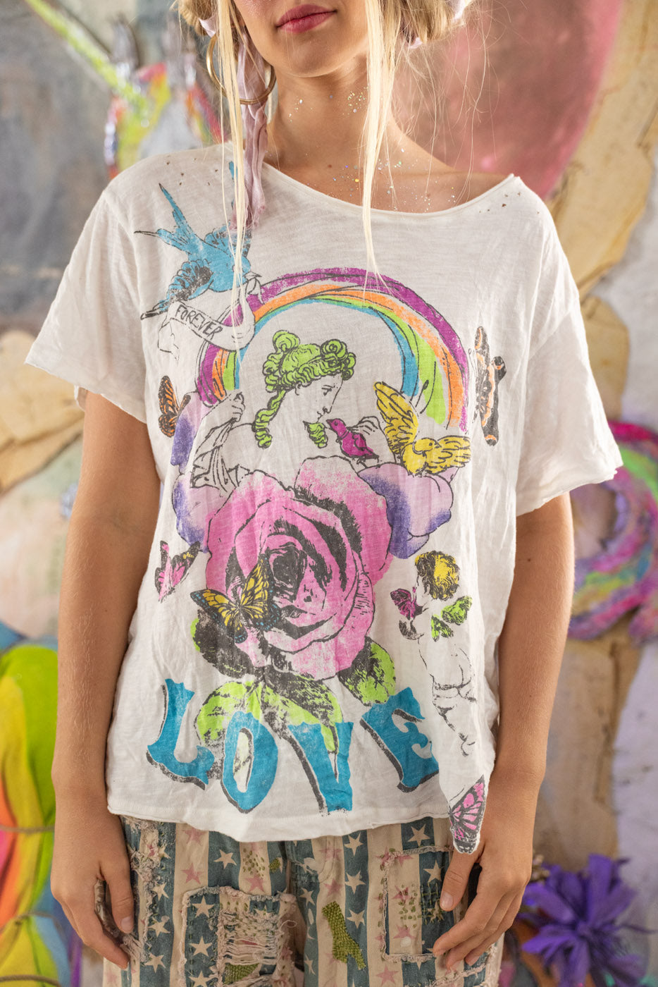 Person wearing a white t-shirt with colorful rainbow graphic designs and the word 'LOVE'.