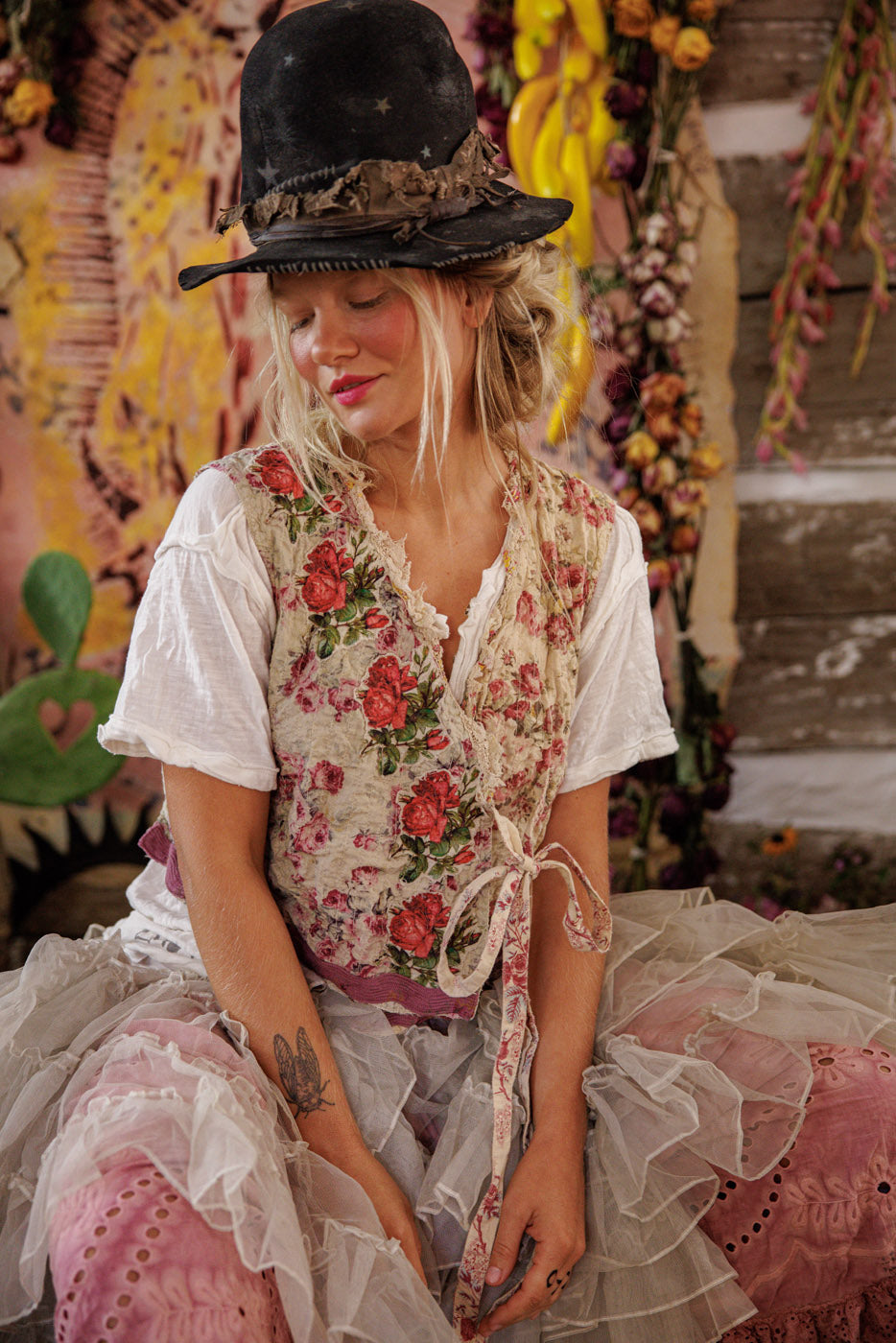 Woman in Magnolia Pearl artisan floral vest and ruffled skirt, whimsical vintage style setting