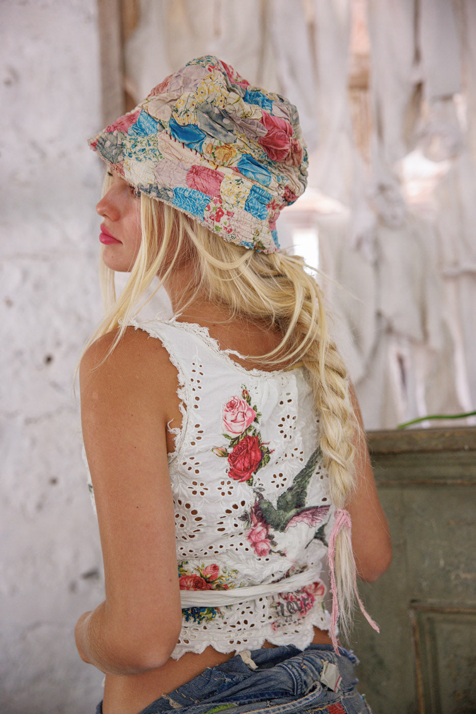 Woman in Magnolia Pearl artisan patchwork hat and vintage floral eyelet top with braided hair