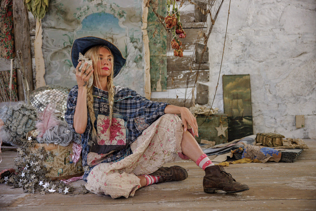 Woman in Magnolia Pearl artisan clothing with vintage floral skirt, plaid top, and whimsical decor