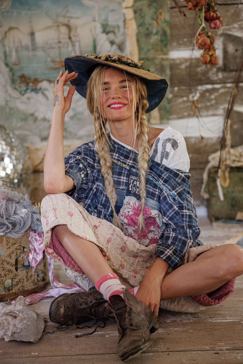 Woman in Magnolia Pearl artisan clothing with whimsical, vintage style sitting on rustic floor