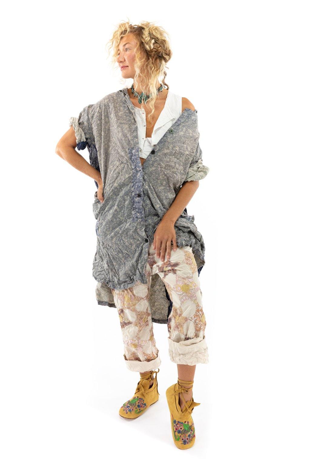 Woman in oversized blue patterned dress, floral pants, yellow embroidered boots, white background