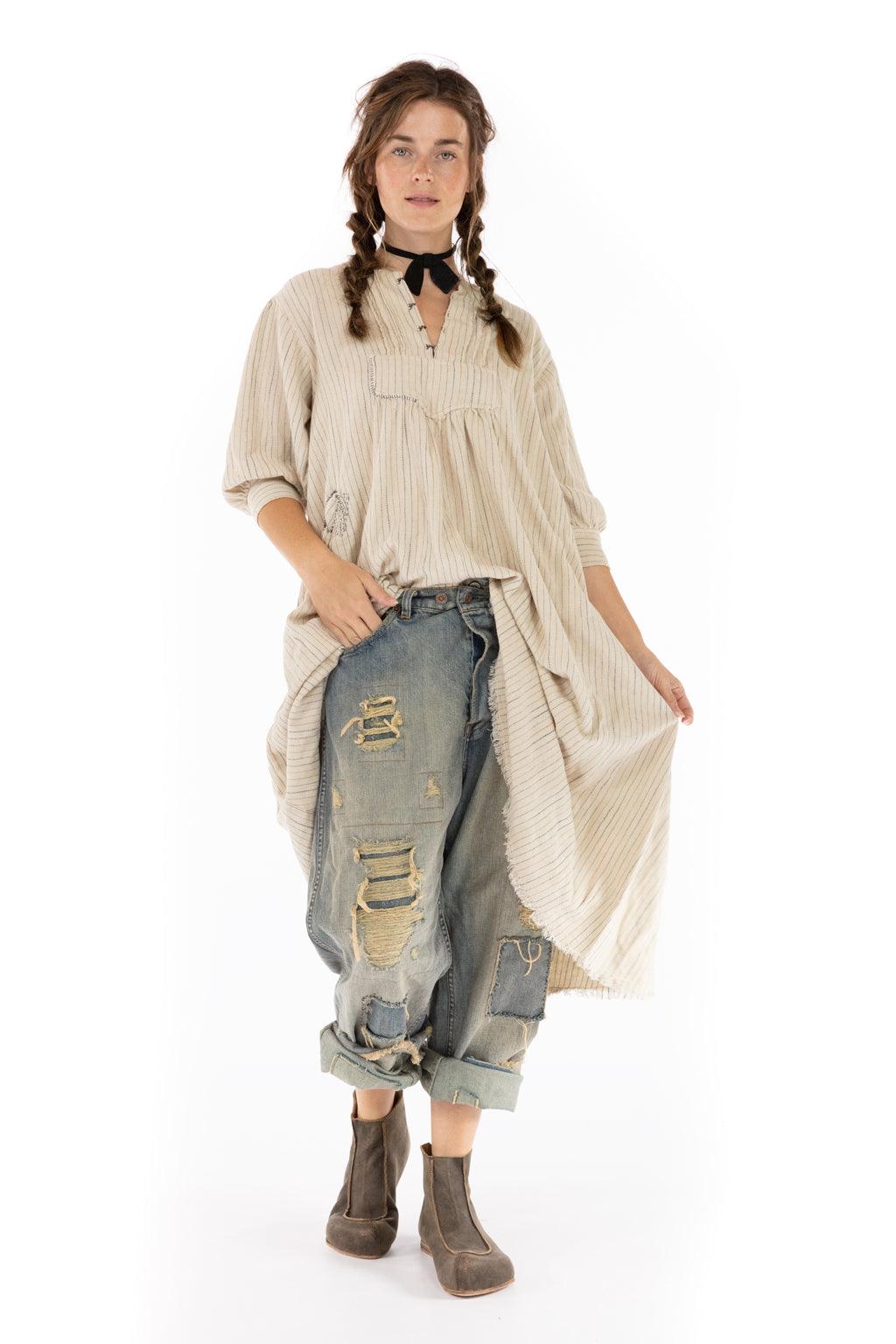 Woman in striped beige tunic, distressed jeans, brown boots on white background