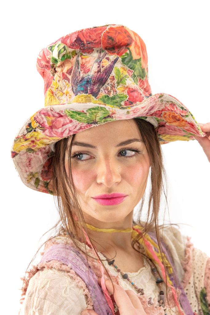 Woman in Magnolia Pearl artisan vintage floral hat with whimsical bird design and colorful clothing