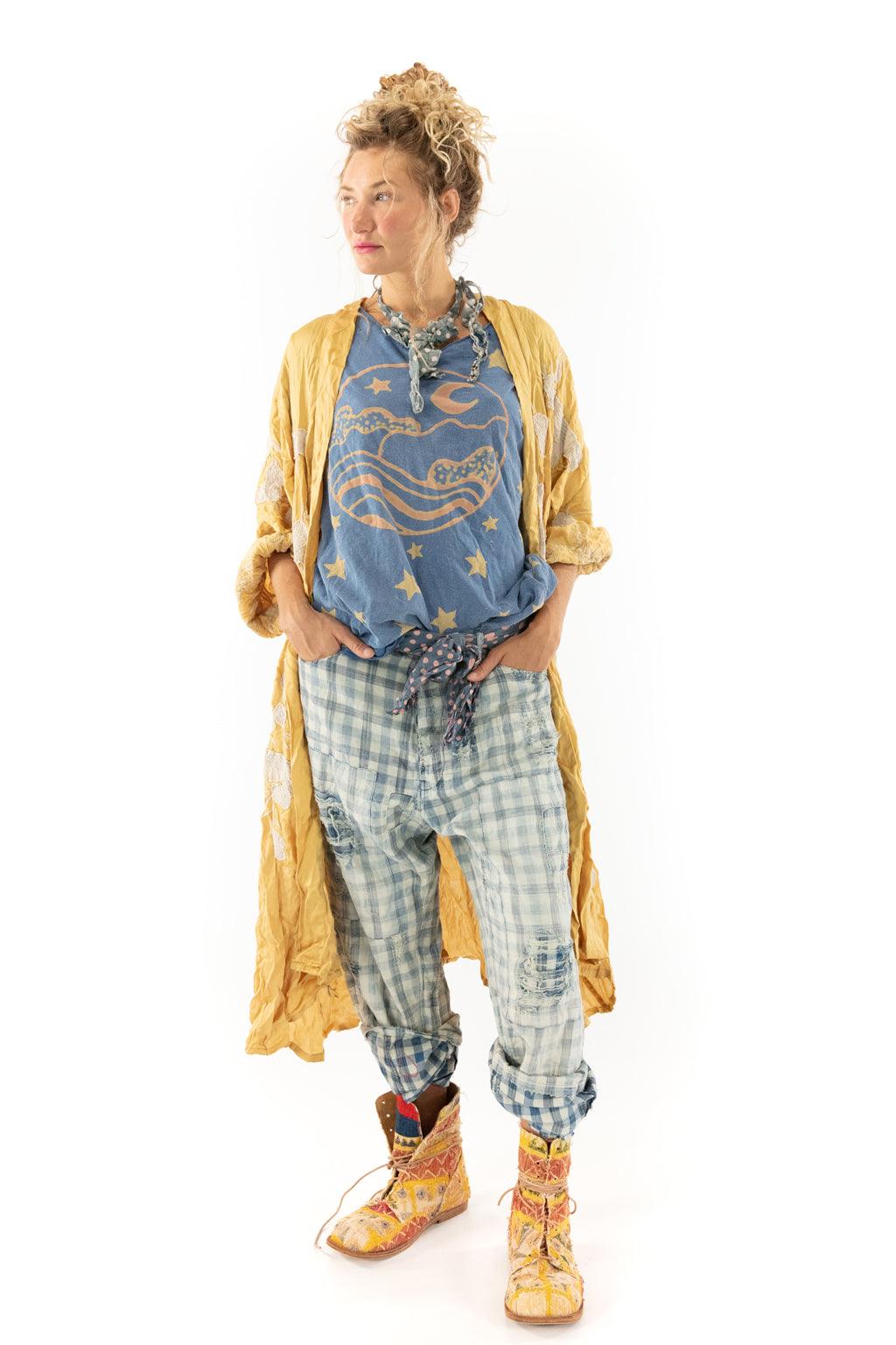 Woman in Magnolia Pearl yellow vintage coat, blue whimsical shirt, plaid pants, artisan boots