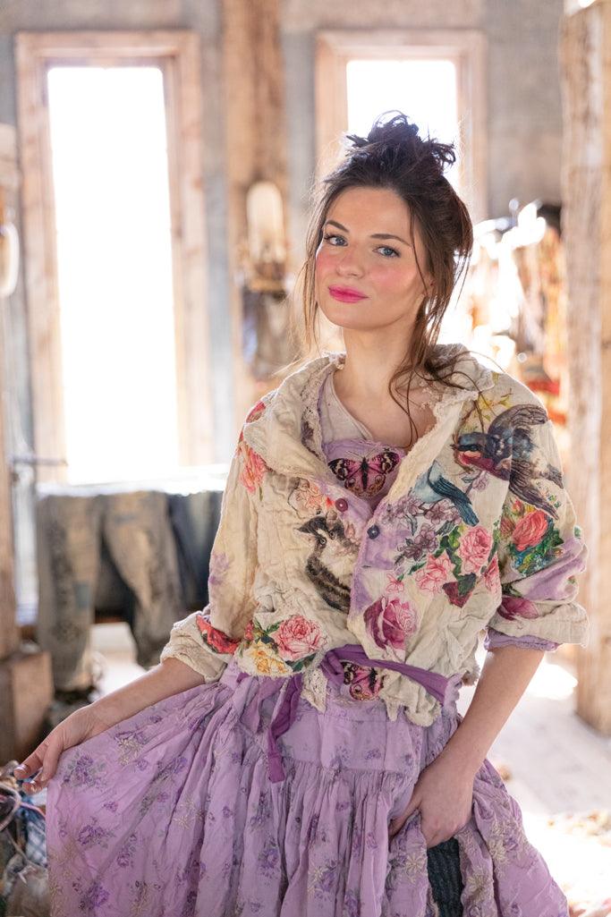 Woman in Magnolia Pearl artisan jacket with bird and floral prints, vintage lavender dress