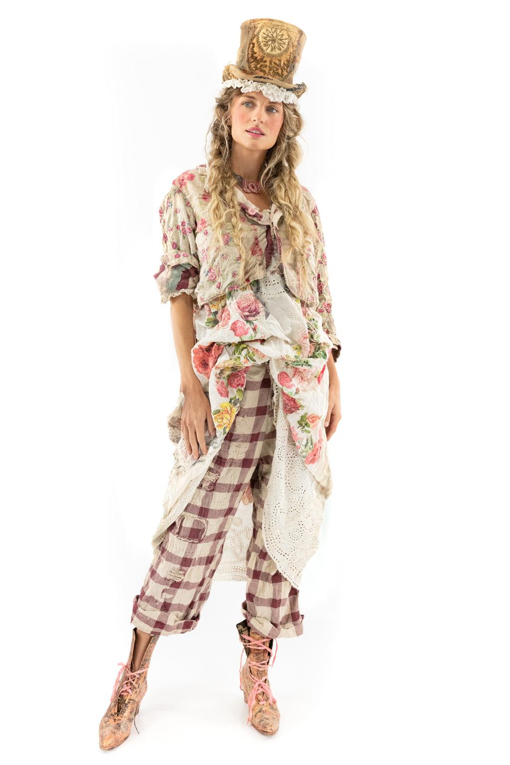 Woman in Magnolia Pearl whimsical floral quilted jacket, vintage-style artisan top hat, checkered pants, and lace boots